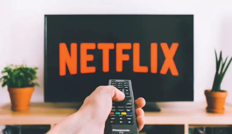 man pointing tv remote at netflix tv